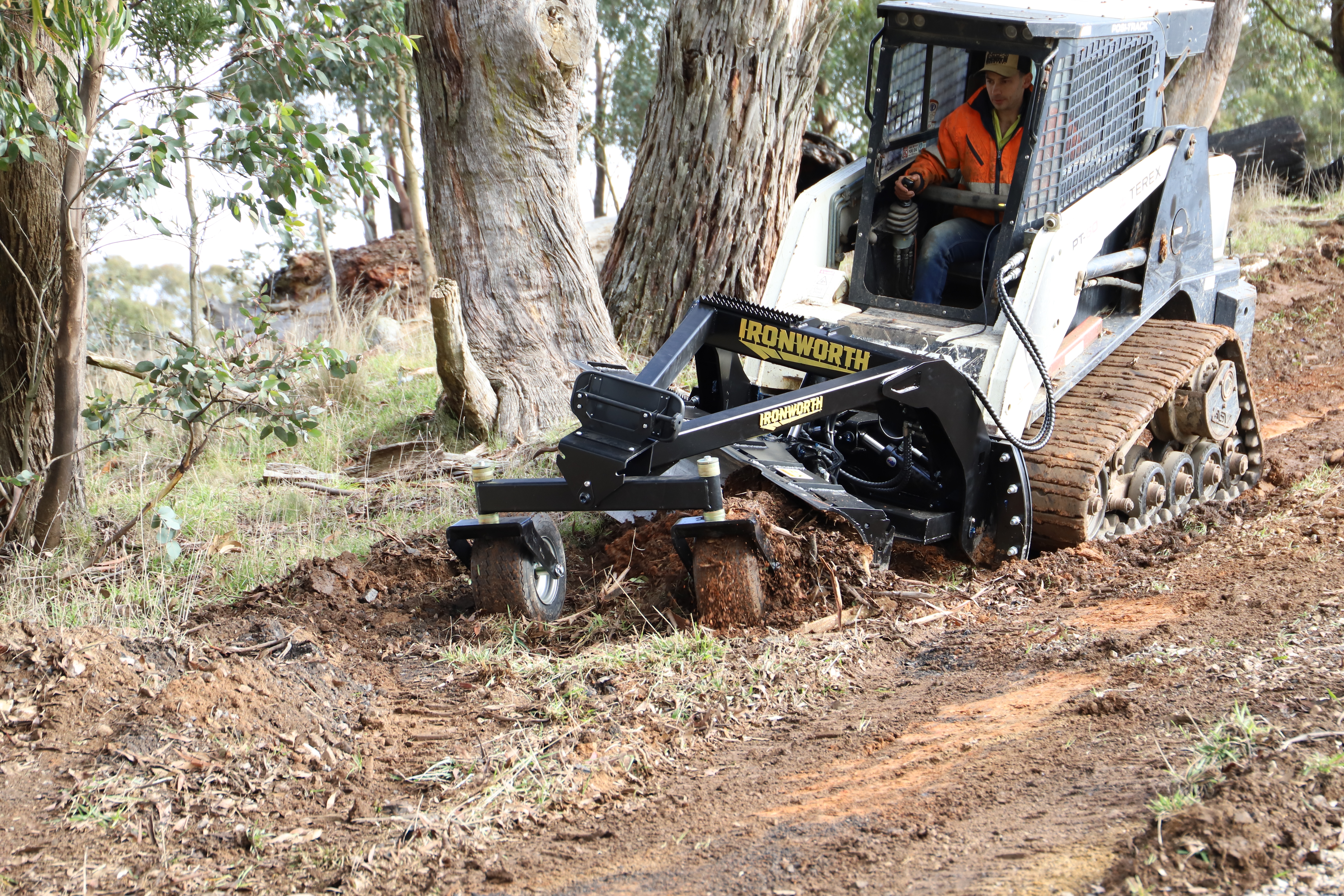 An IRONWORTH PAT-Grader finishing a sloped track beside gum trees