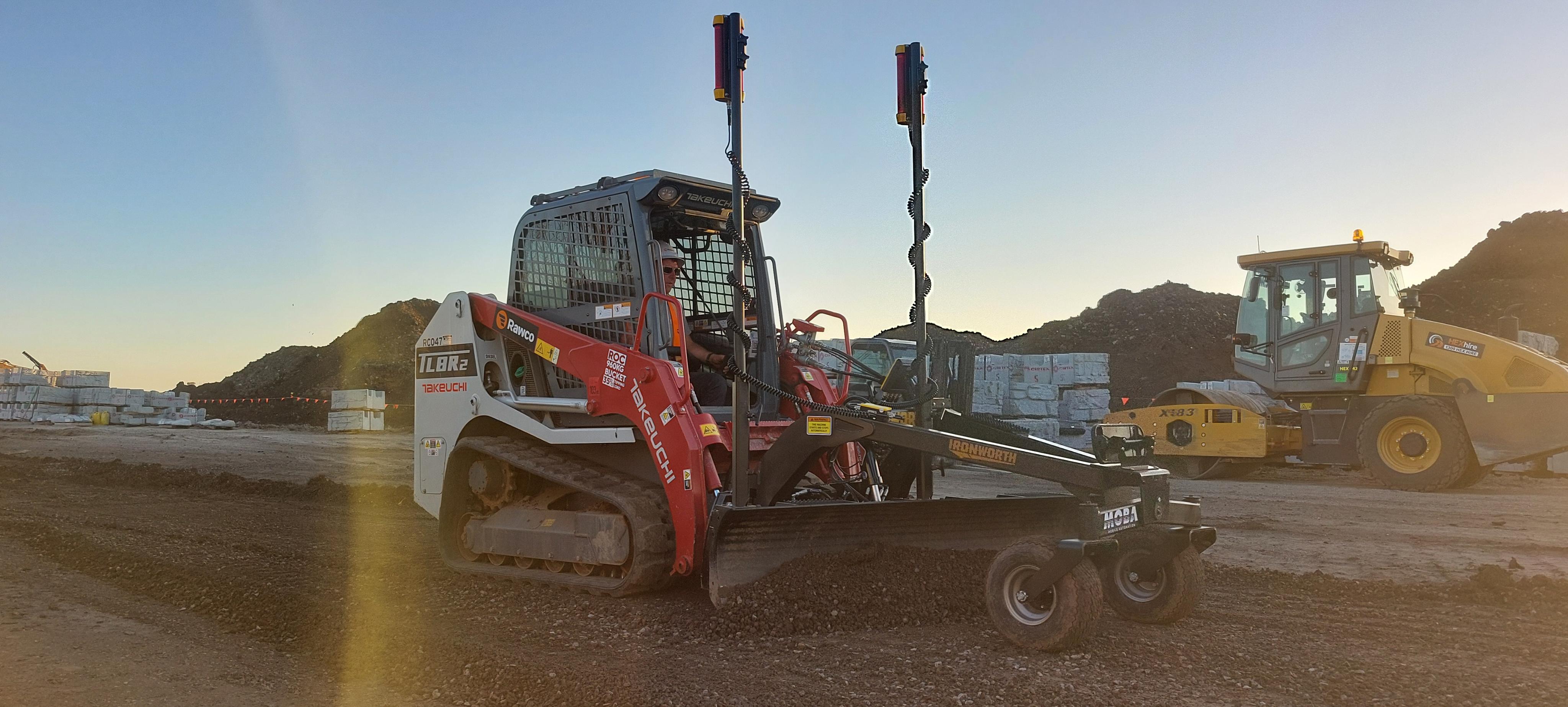 Ironworth PAT-Grader blade grading a gravel surface behind a compact track loader on a job site